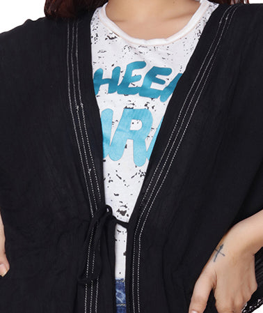 Close-up of black embroidered polyester coverup with tie detail, worn over a casual graphic t-shirt.