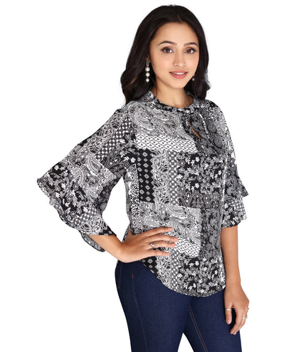 Angled view of a black and white printed polyester top, emphasizing its relaxed fit and fashionable pattern.